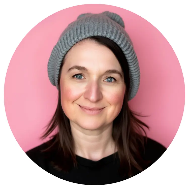 Person mit grauer Mütze und schwarzem Hemd, lächelt vor rosa Hintergrund. Person mit grauer Mütze und schwarzem Hemd, lächelt vor rosa Hintergrund.